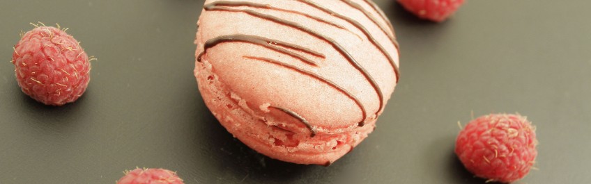 Macaron garni d’une ganache faite d’une purée de framboises, décoré d’une petite touche de chocolat noir